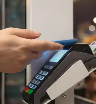 Pessoa usando smartphone azul para realizar pagamento por aproximação em uma máquina de cartão moderna, destacando conveniência e tecnologia contactless