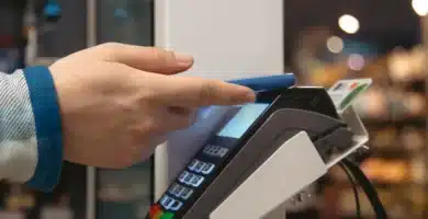 Pessoa usando smartphone azul para realizar pagamento por aproximação em uma máquina de cartão moderna, destacando conveniência e tecnologia contactless