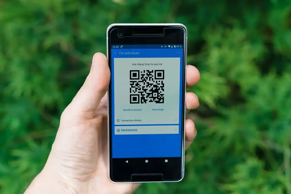 Smartphone exibindo um QR Code para pagamento, em um fundo verde natural, representando inovação e praticidade nas novas funcionalidades do Pix.