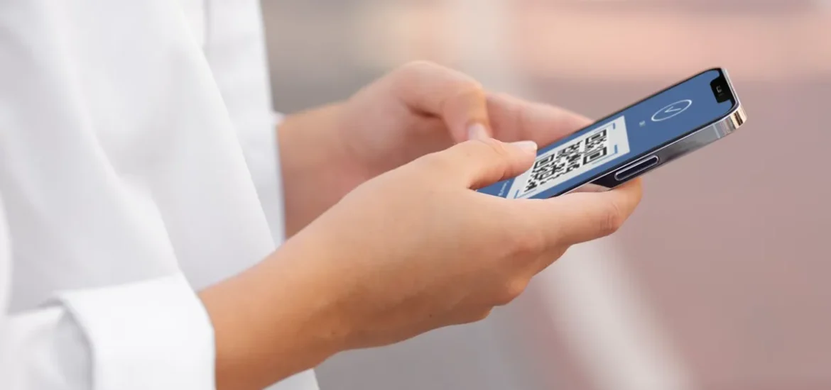 Pessoa segurando um smartphone exibindo um código QR em uma tela azul para pagamento digital.