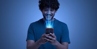 Homem sorrindo enquanto utiliza um smartphone com feixes de luz azul representando tecnologia avançada e inteligência artificial.