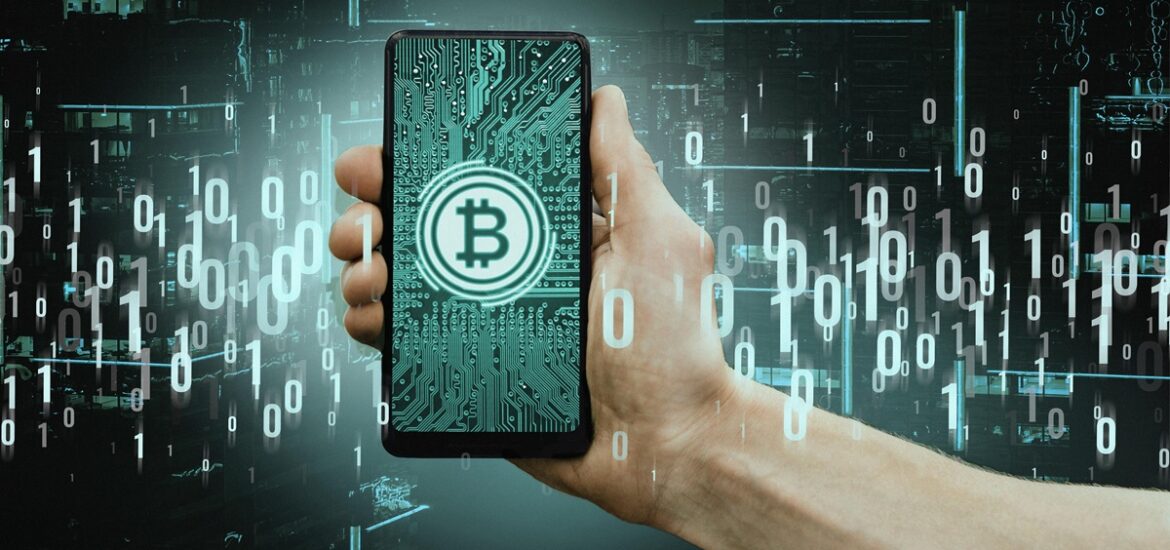 Mão segurando um smartphone com símbolo de Bitcoin na tela, representando pagamentos digitais e integração entre criptomoedas e sistemas financeiros tradicionais. No fundo, códigos binários e uma cidade digital simulam o conceito de blockchain e transações digitais seguras.