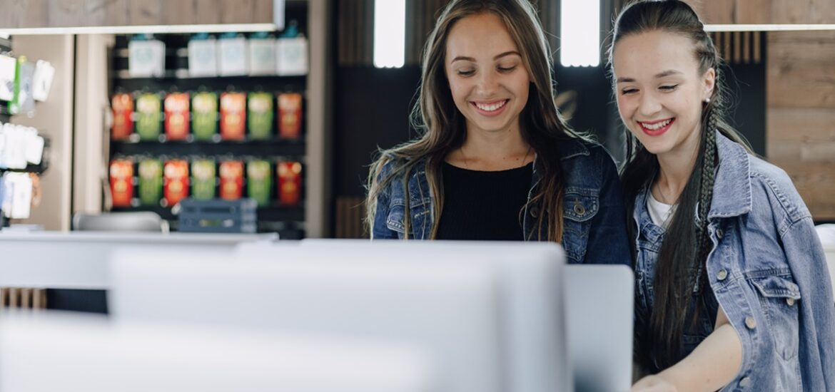 Duas mulheres sorridentes observando produtos em um ambiente comercial moderno, representando o impacto positivo do crescimento das microempresas no Brasil.