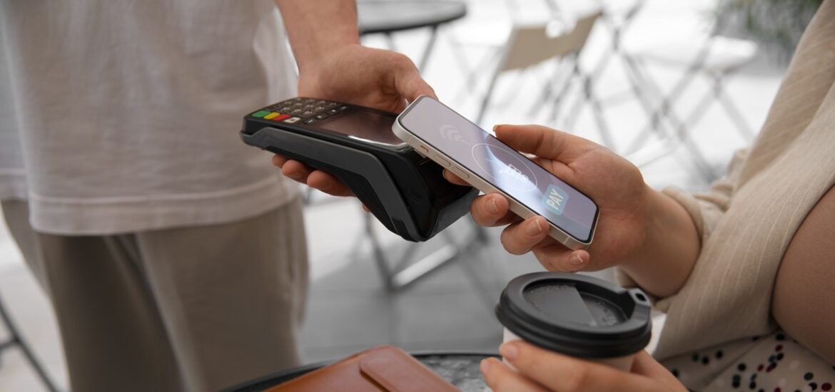 Pessoa realizando pagamento via smartphone com tecnologia de aproximação em uma maquininha de cartão.